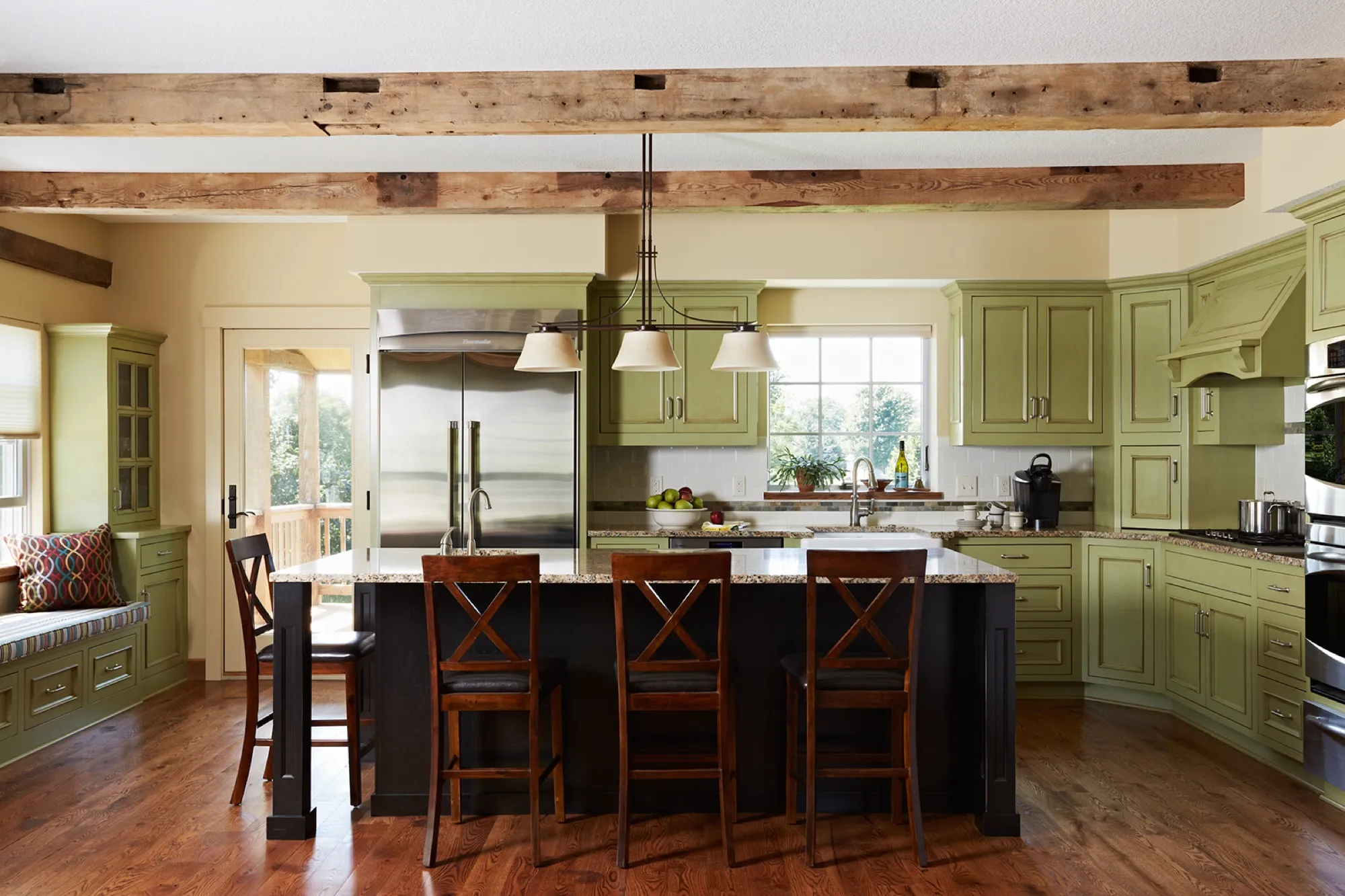 Finished kitchen with painted cabinetry, exposed beams, and a central island.