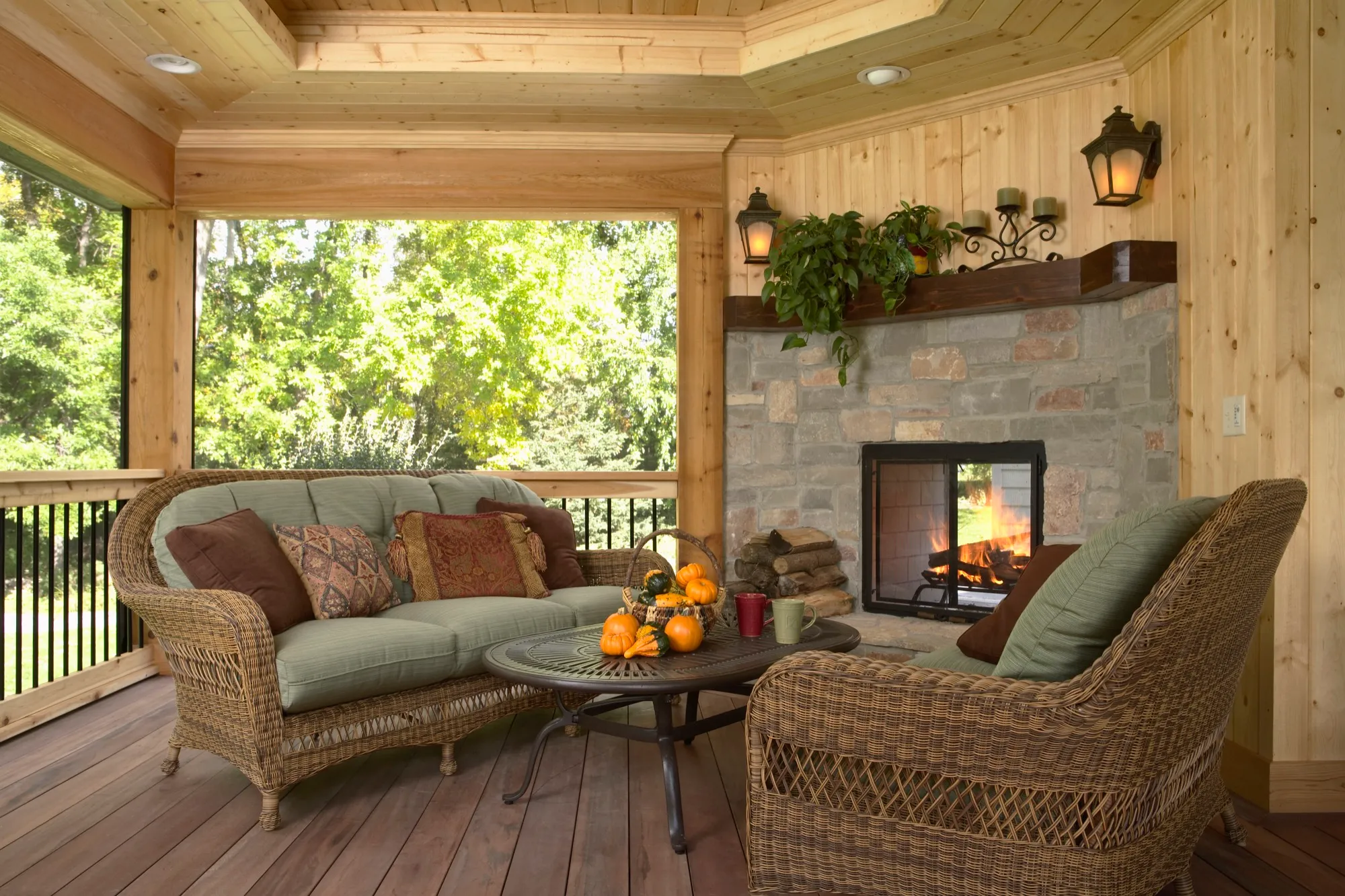 Covered porch interior with wood ceiling, fireplace, and seating area.